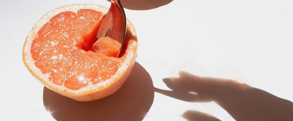 Pink grapefruit half with spoon, sunlight shadows - energy vitality notes